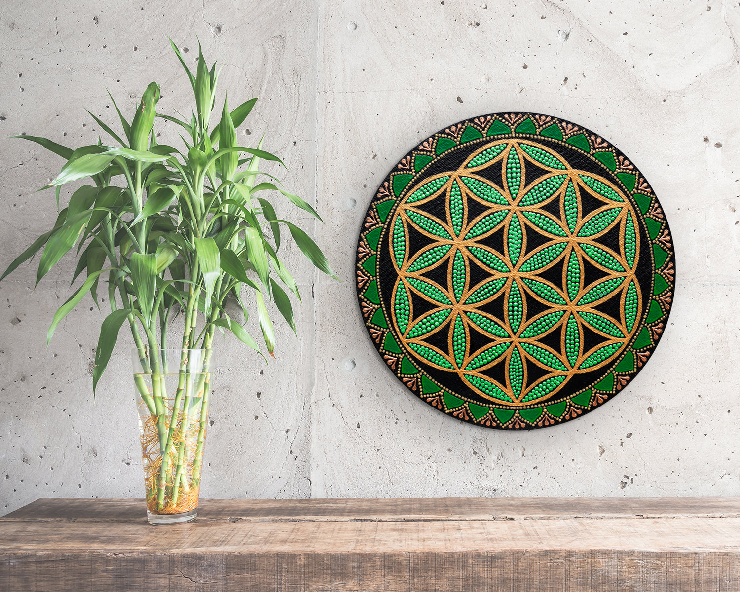 Flower of Life painted on a round canvas board 30 cm, dot art technique, green colors. Front view on a wall, plant stands on the side.