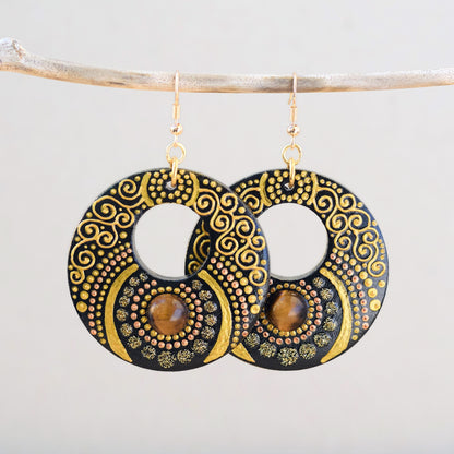 Wooden painted earrings with an inlaid Tiger Eye cabochon, decorated with fine golden swirls and textured dot motifs.