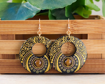 Wooden painted earrings with golden motif on a wooden stand
