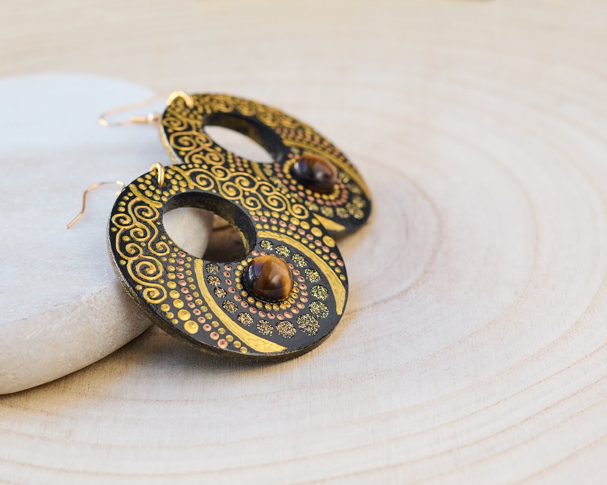 Wooden painted earrings with golden motif on a wooden background