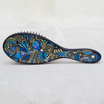 Wooden hairbrush with blue and gold patterns on a light gray background