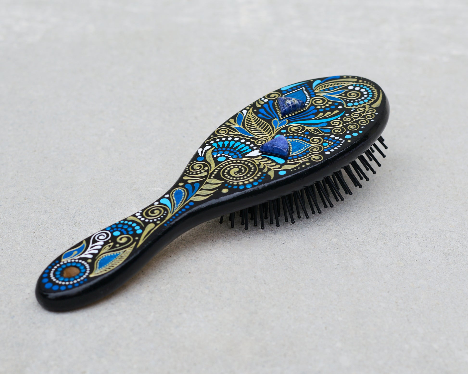 Decorative hairbrush with blue and gold patterns on a light gray background
