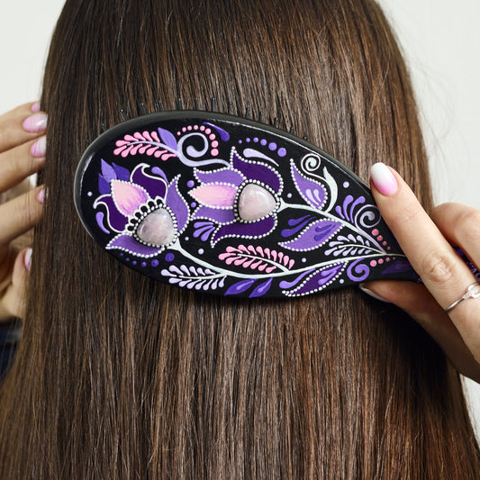 Woman using a decorative wooden purple hairbrush on her hair