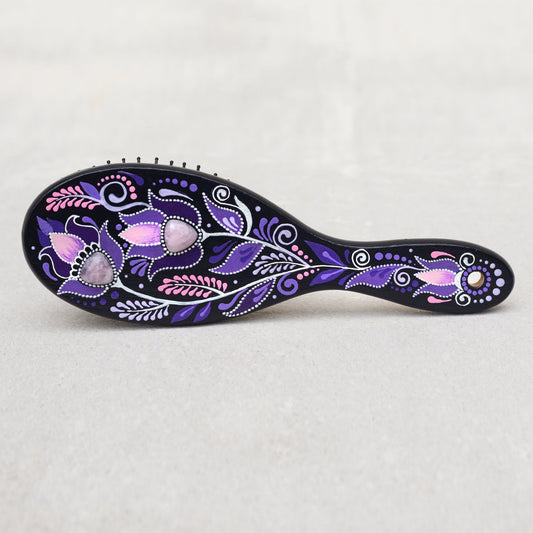 Wooden hand-painted hairbrush with purple and pink floral patterns on a light gray background