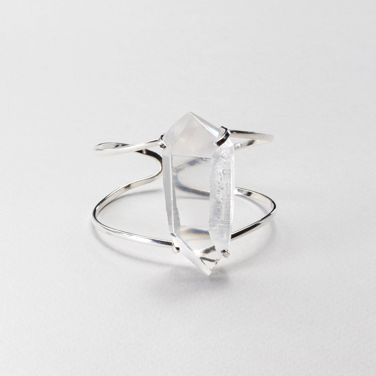 A silver chunky bracelet featuring a clear crystal, photographed on a light gray background.