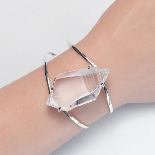 Clear crystal bracelet on a wrist against a neutral background