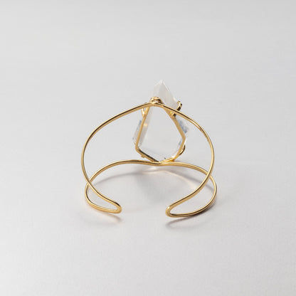 Gold wire bracelet with a white stone on a light gray background