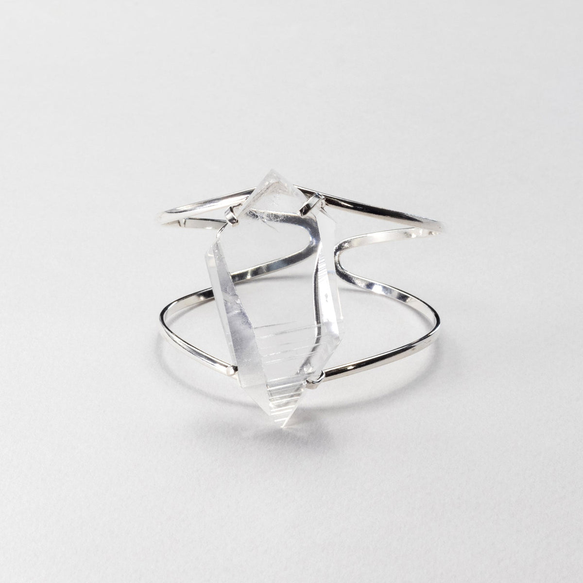 Silver bracelet, featuring a large, faceted clear crystal on a light gray background