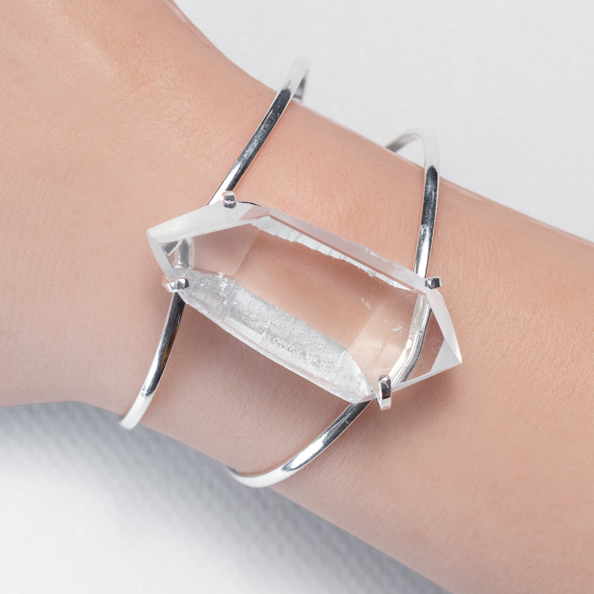 Silver freeform faceted bracelet on a wrist with a clear stone