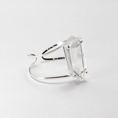 A silver-toned bracelet featuring a large, clear rectangular gemstone, photographed on a clean, light gray background.