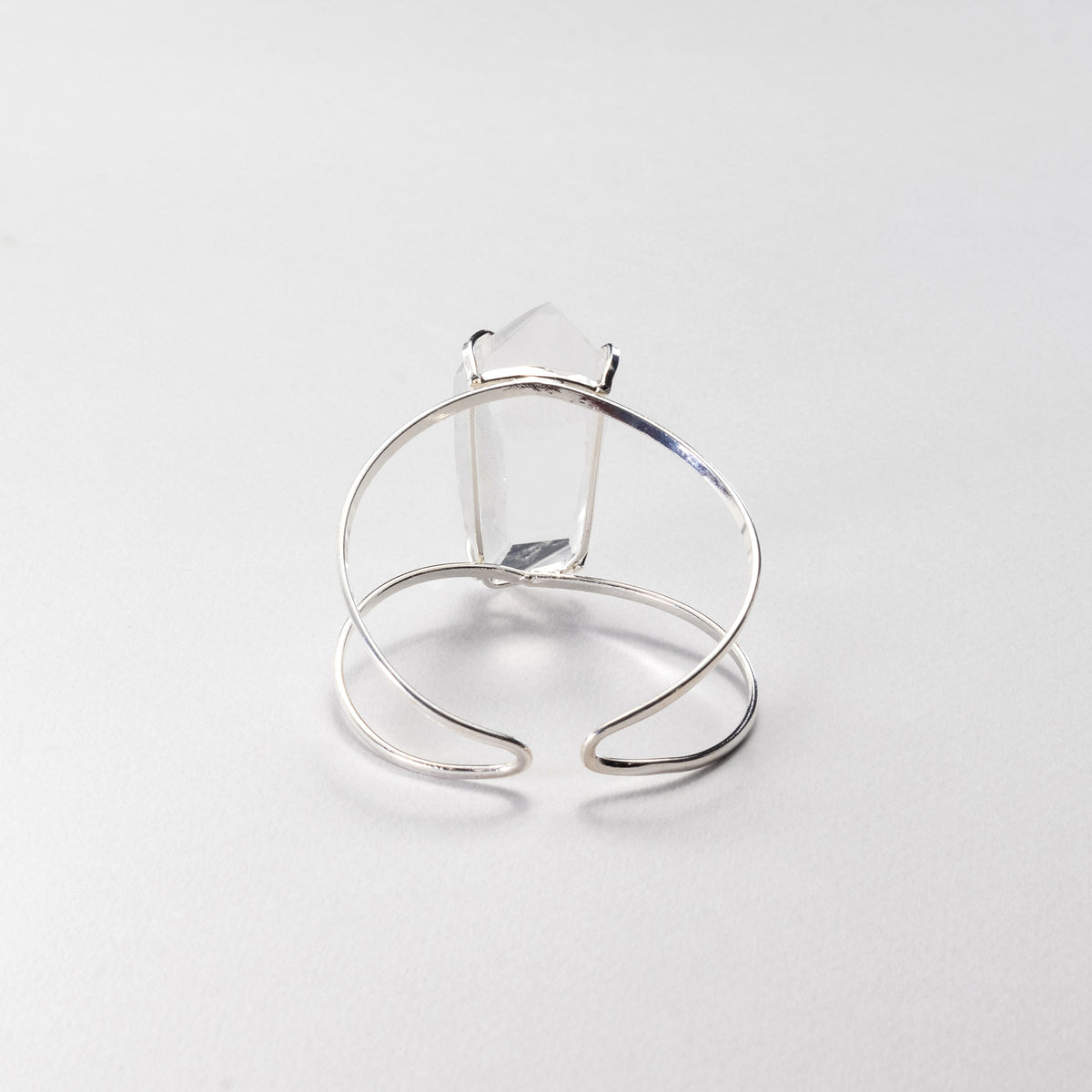 A silver-toned bracelet featuring a large, clear rectangular gemstone, photographed on a clean, light gray background.