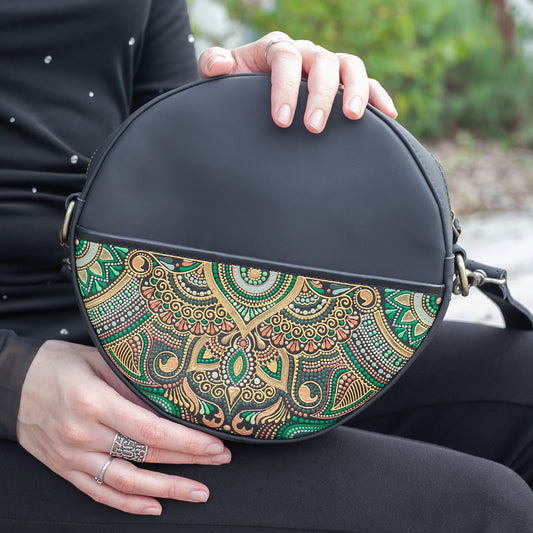 Person holding a black round bag with a colorful floral design.