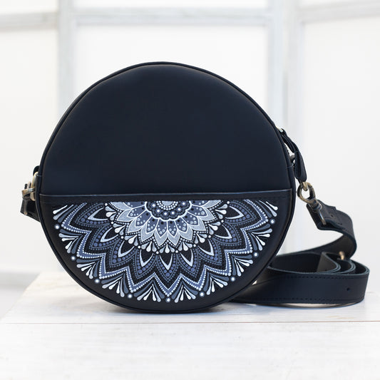 Black round handbag with white mandala design on a white background