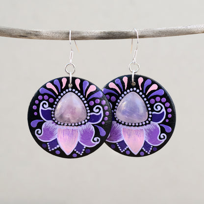 Wooden earrings with purple and pink floral design and rose quartz cabochon on a gray background