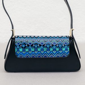 Black leather bag with hand-painted blue design standing on a white table, front view