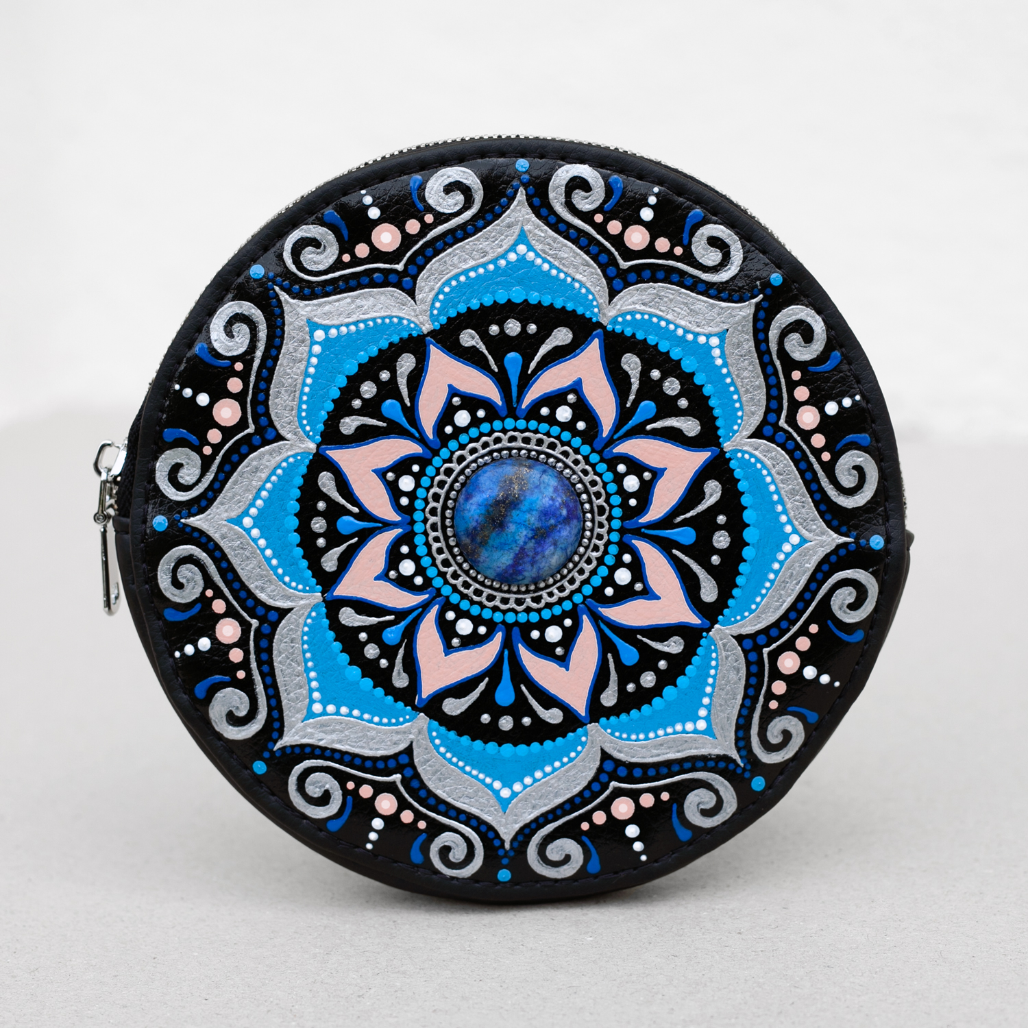 Round leather wallet with blue mandala painting and lapis lazuli stone in the center. Front view, light gray background.