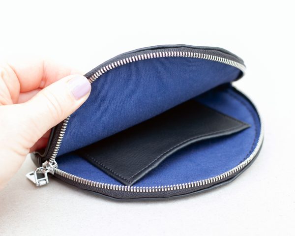 Close-up view of the hand opening wallet with denim blue cotton lining inside and a small leather pocket.